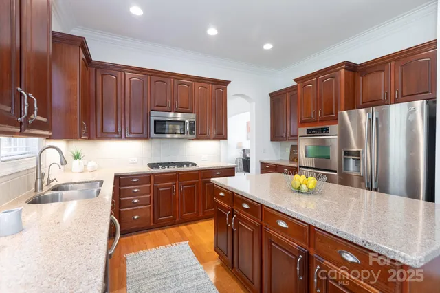 a kitchen with stainless steel appliances wooden cabinets a sink and a stove