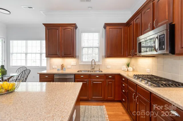 a kitchen with stainless steel appliances granite countertop a stove a sink and a microwave
