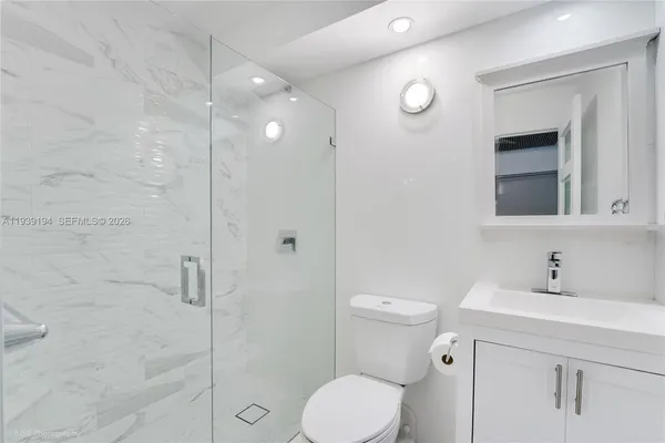 a bathroom with a toilet sink vanity granite and shower