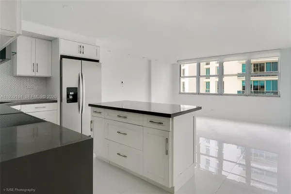 a kitchen with white cabinets and window