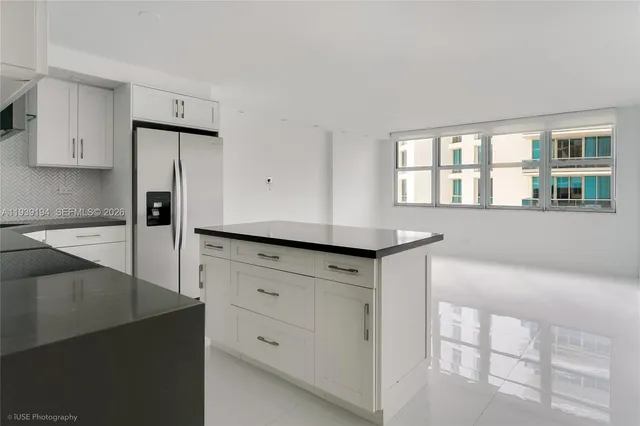 a kitchen with white cabinets and window