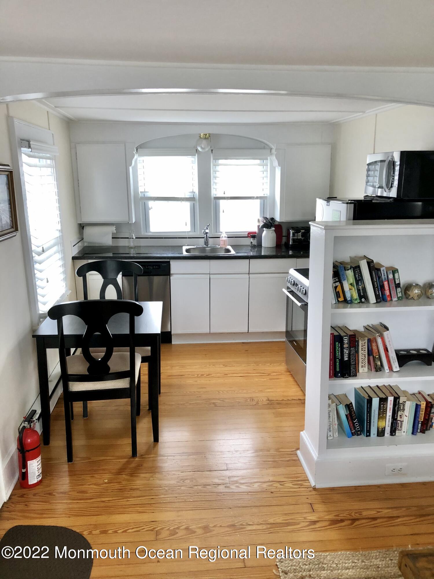106 Lincoln Lane, Unit WINTER RENTAL Avon-by-the-Sea, NJ 07717 - Photo 5 of 11 a kitchen with stainless steel appliances granite countertop a table chairs and a refrigerator