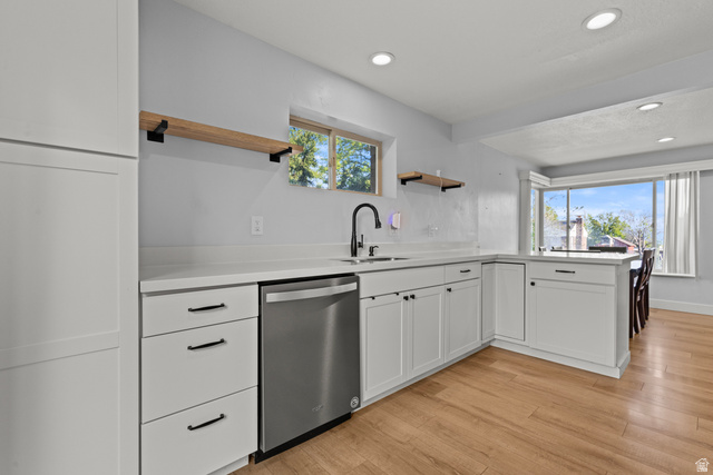 2101 West 3900th Street South Roy, UT 84067 - Photo 20 of 36 Kitchen featuring white shaker cabinetry, light-toned countertops, wood-finish flooring, a stainless steel dishwasher, and a black gooseneck faucet