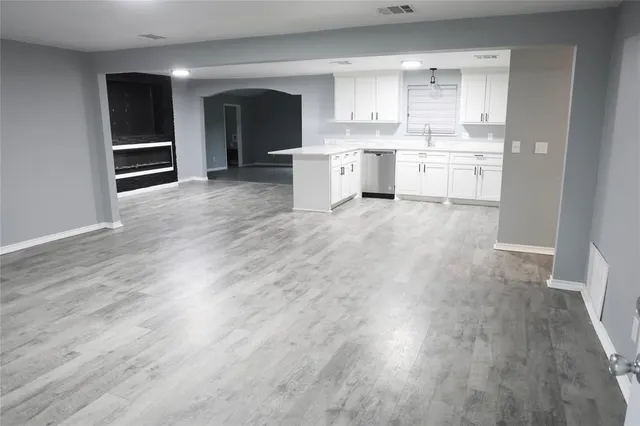 a large kitchen with cabinets a sink and dishwasher a oven with wooden floor