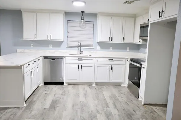 a kitchen with white cabinets stainless steel appliances and sink