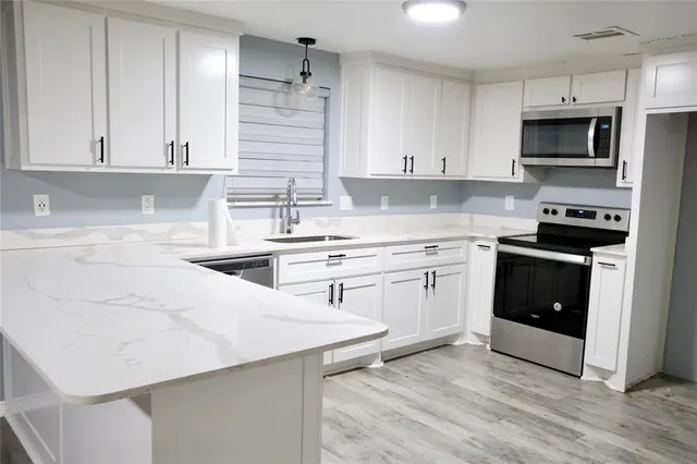 a kitchen with white cabinets stainless steel appliances and sink