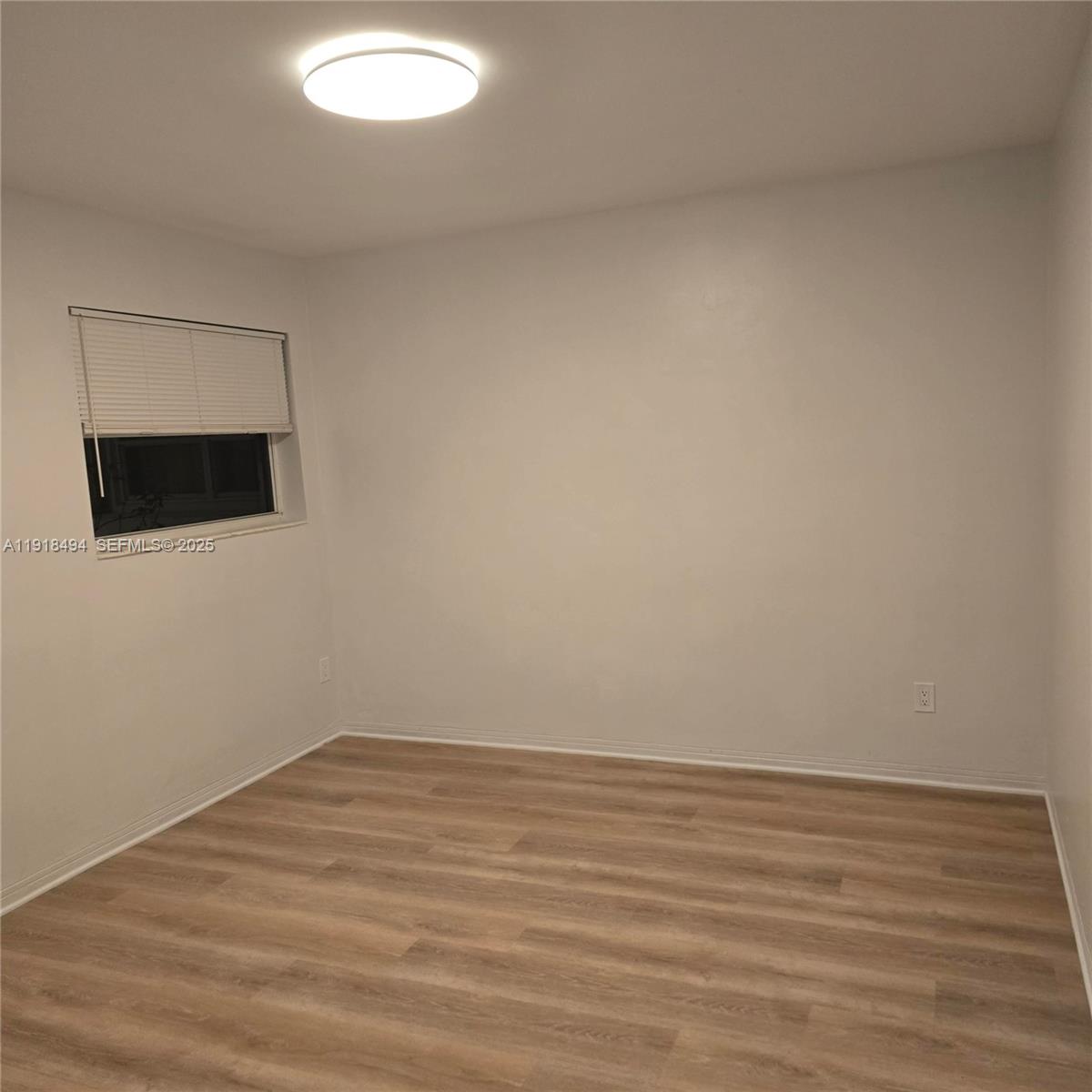 122 Northwest Boulevard, Unit B Miami, FL 33126 - Photo 13 of 17 a view of an empty room with wooden floor and a window