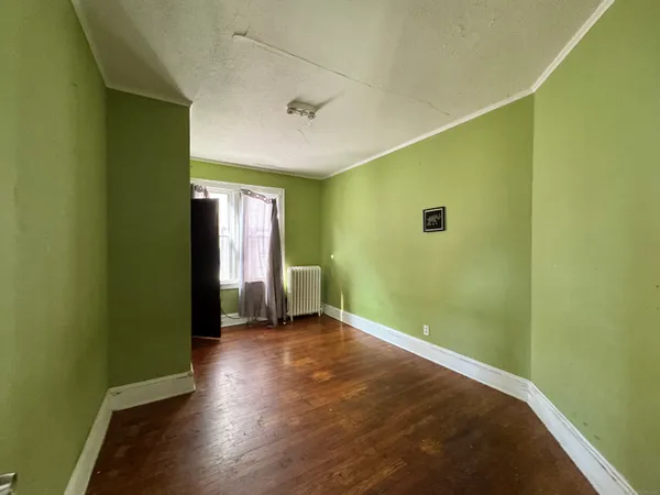 a view of an empty room with a window and wooden floor
