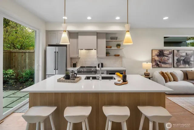 a kitchen with stainless steel appliances granite countertop a table chairs refrigerator and sink