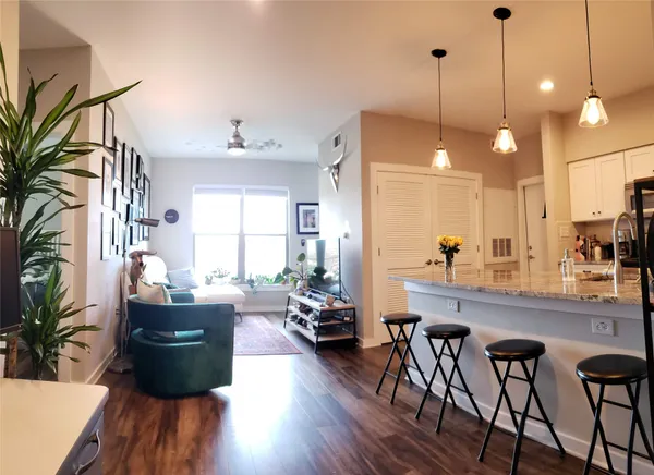 a kitchen with stainless steel appliances granite countertop wooden floors wooden cabinets dining table and chairs