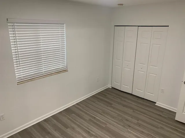 a view of empty room with wooden floor and floor to ceiling window