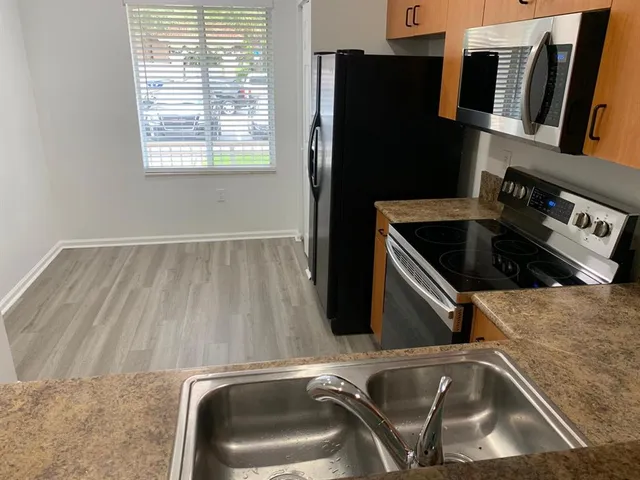 a kitchen with stainless steel appliances granite countertop a refrigerator and a stove top oven
