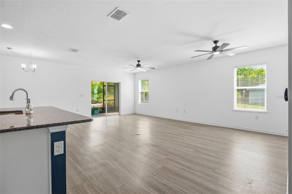 4322 Kiska Road North Port, FL 34288 - Photo 11 of 37 an empty room with wooden floor chandelier fan and windows