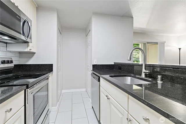 a kitchen with granite countertop a sink stainless steel appliances and cabinets
