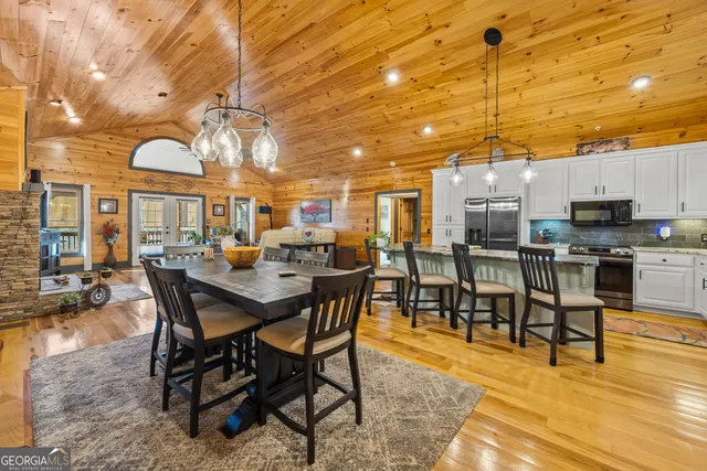 a kitchen with stainless steel appliances granite countertop a stove a sink a dining table and chairs with wooden floor