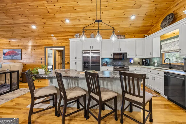 a dining room with wooden floor a chandelier a wooden table and chairs
