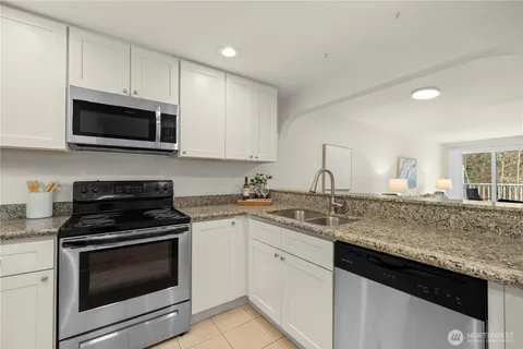 a kitchen with granite countertop a sink stainless steel appliances and white cabinets