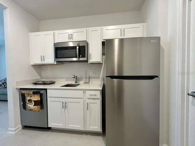 a kitchen with stainless steel appliances granite countertop a refrigerator a stove a sink and white cabinets