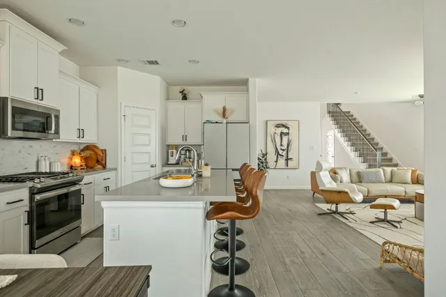 a living room with furniture a flat screen tv and kitchen view