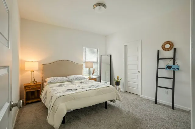 a bedroom with a bed and a dresser with wooden floor
