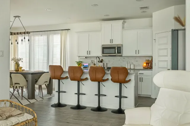 a kitchen with stainless steel appliances a dining table chairs and a refrigerator
