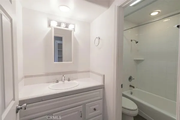 a bathroom with a granite countertop sink a toilet and shower