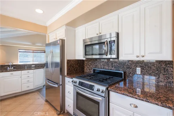 a kitchen with granite countertop a sink stove and refrigerator