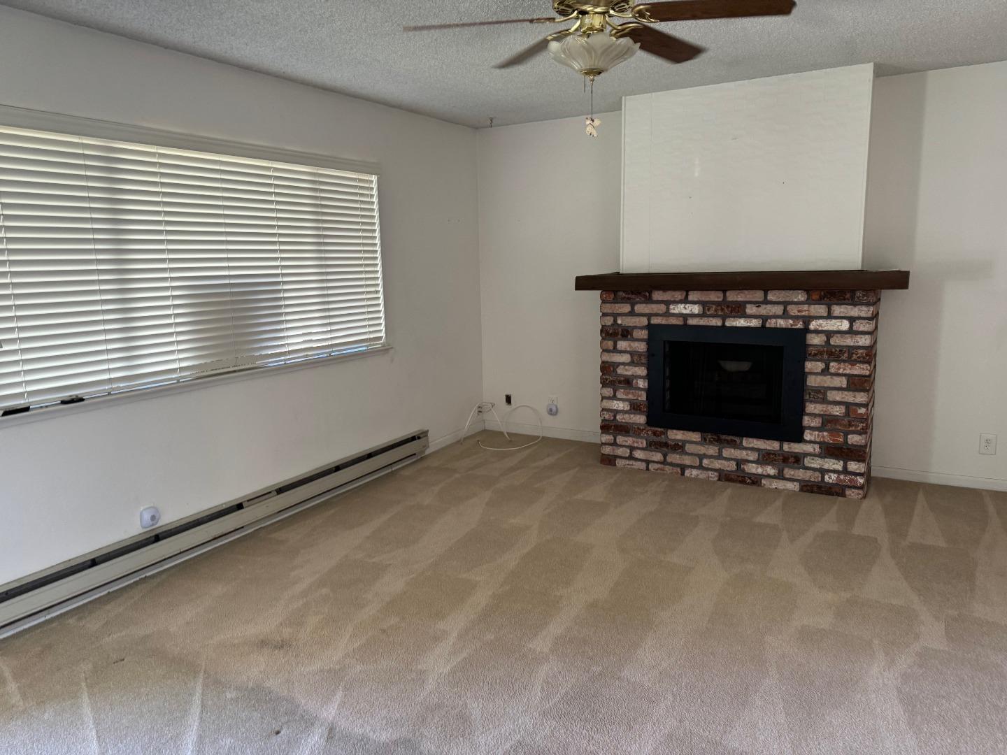 1261 Juniper Drive, Unit 12 Gilroy, CA 95020 - Photo 4 of 9 an empty room with a fireplace and windows