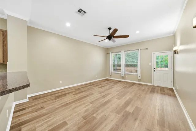 a view of an empty room with wooden floor and a window