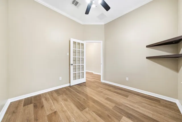 an empty room with wooden floor closet and windows