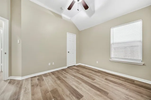a view of an empty room with window and a ceiling fan