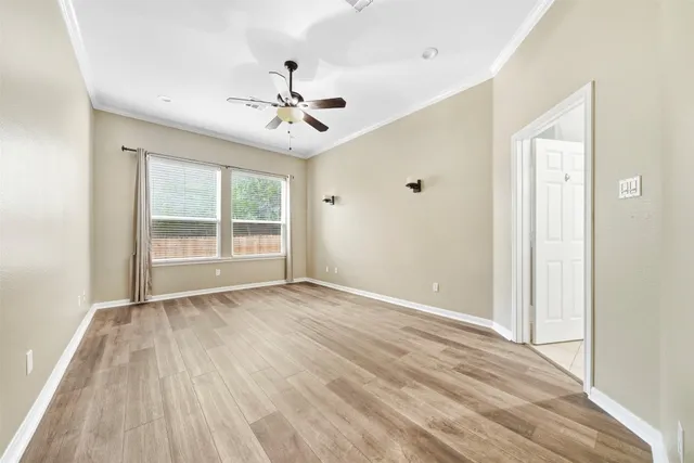 an empty room with wooden floor ceiling fan and windows