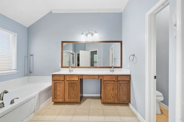 a bathroom with a bathtub a double vanity sink and mirror