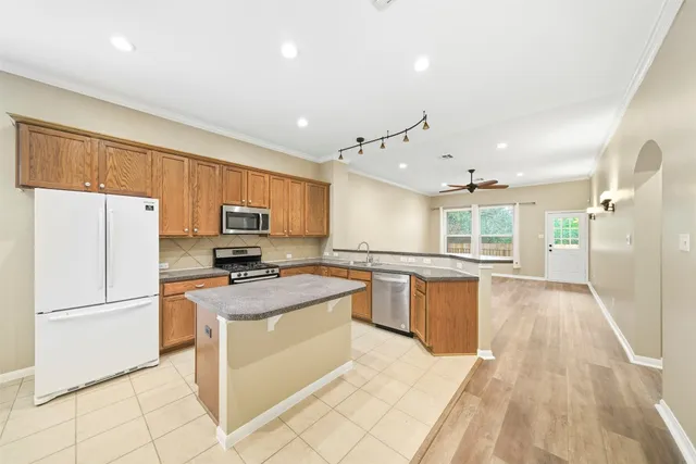 a kitchen with granite countertop a refrigerator stove top oven and sink