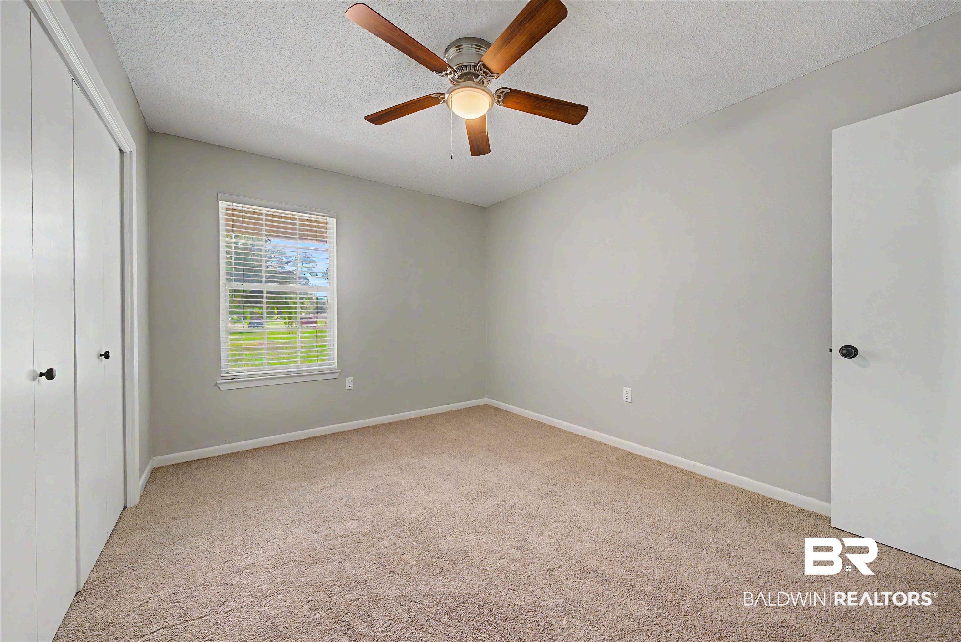 22963 Highway 98 Foley, AL 36535 - Photo 22 of 52 Carpeted interior room featuring a ceiling fan with light fixture, window with blinds, and white bi-fold closet doors