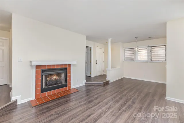 an empty room with wooden floor fireplace and windows