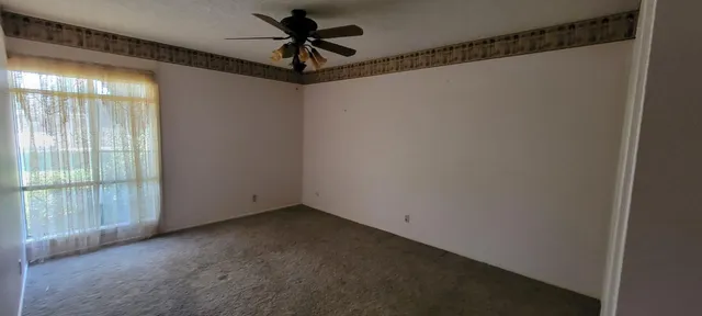 a view of a room with a ceiling fan and window
