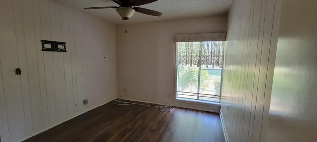 a view of an empty room with a window and wooden floor