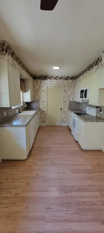 a large kitchen with stainless steel appliances a large counter top a stove and a wooden floors