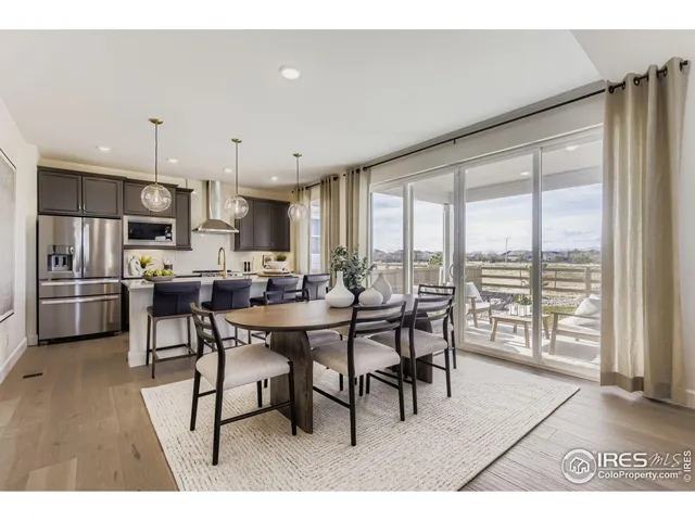 a open kitchen with stainless steel appliances granite countertop a stove a refrigerator a sink a dining table and chairs with wooden floor