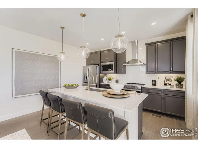 a kitchen with kitchen island granite countertop a sink a stove a microwave a island with wooden floor