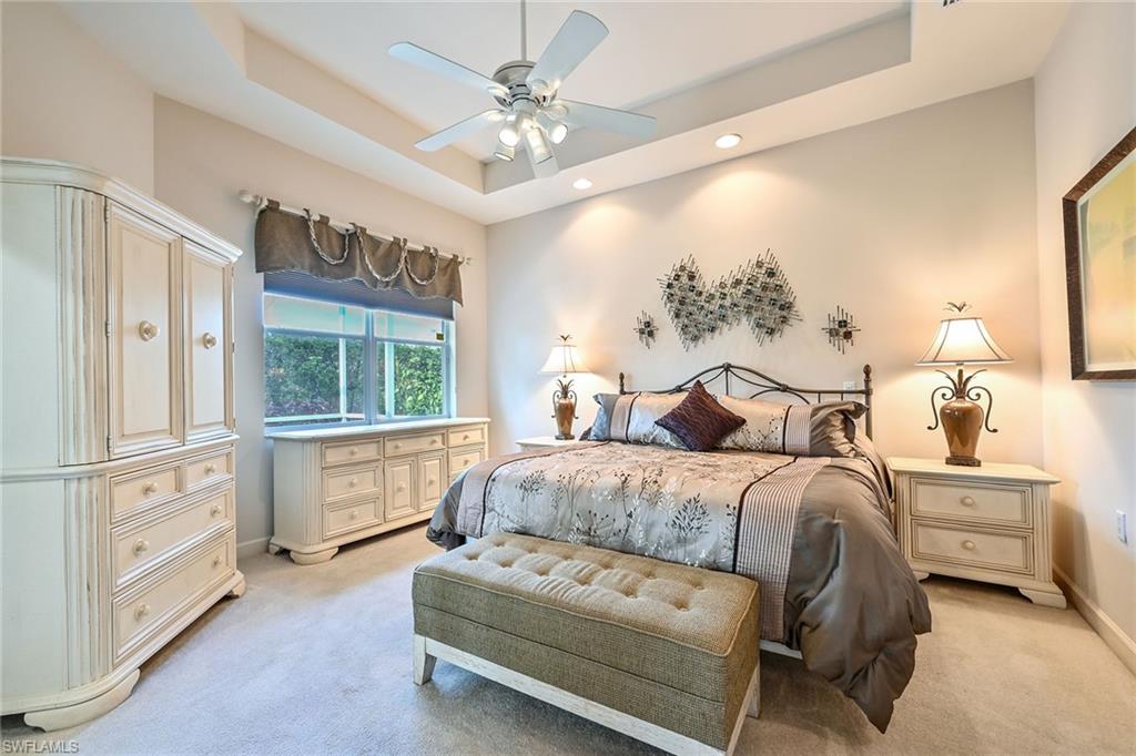 3359 Sandpiper Way Naples, FL 34109 - Photo 16 of 41 a spacious bedroom with a bed a dresser and a chandelier