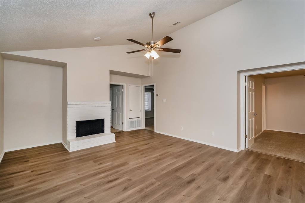1334 Cedar Ridge Drive Lewisville, TX 75067 - Photo 4 of 16 a view of a livingroom with a fireplace a chandelier fan and wooden floor