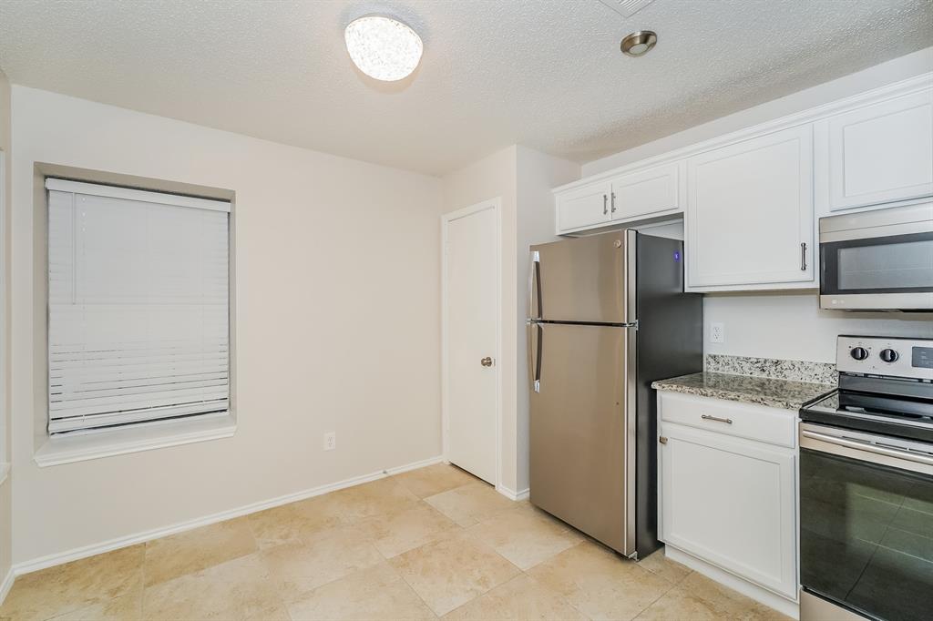 1334 Cedar Ridge Drive Lewisville, TX 75067 - Photo 6 of 16 a kitchen with stainless steel appliances granite countertop a refrigerator a stove a microwave and white cabinets