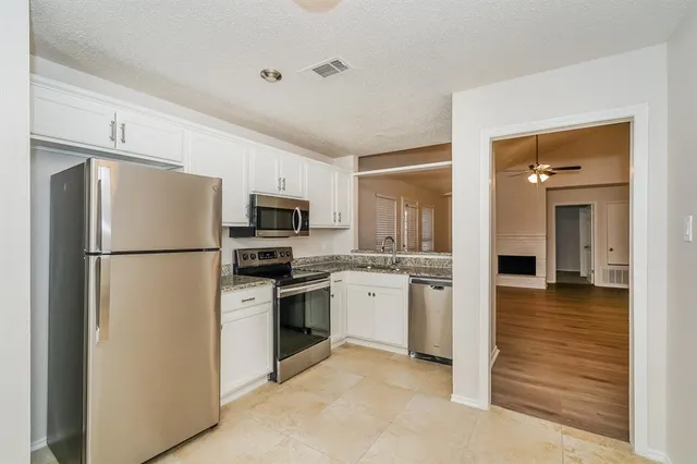 a kitchen with cabinets stainless steel appliances and wooden floor