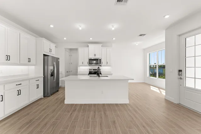 a living room with stainless steel appliances kitchen island hardwood floor and window