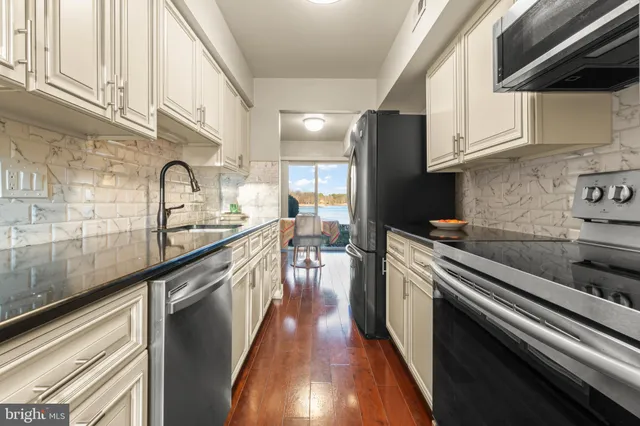 a kitchen with kitchen island granite countertop a sink a counter top space stainless steel appliances and cabinets