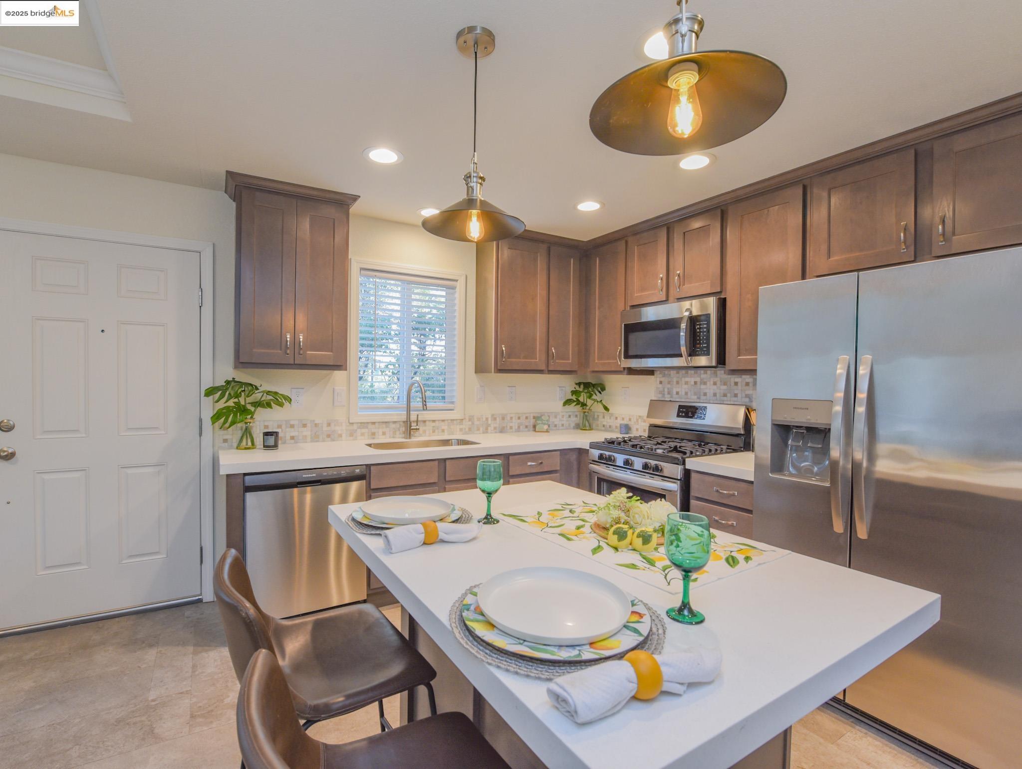 10956 Green Street Columbia, CA 95310 - Photo 11 of 45 Kitchen featuring stainless steel appliances, a kitchen breakfast bar, decorative light fixtures, a center island, and decorative backsplash