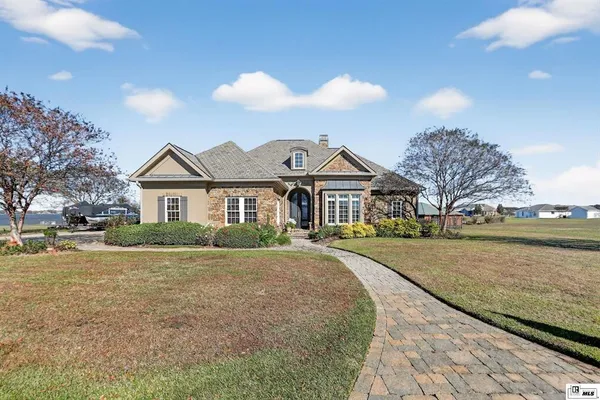 a front view of a house with a yard and lake view