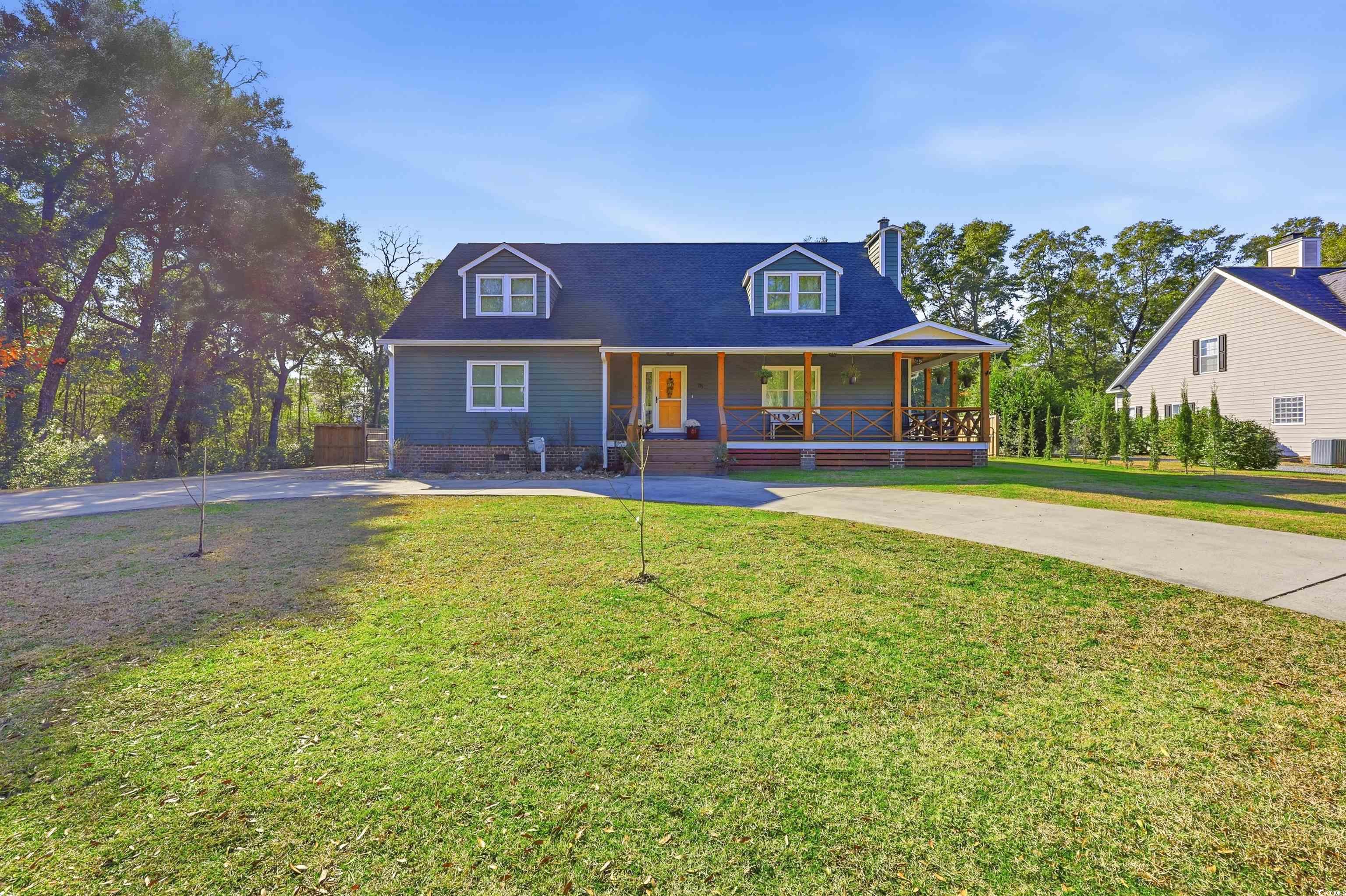 View of front facade with a porch, a front yard, a chimney, and driveway